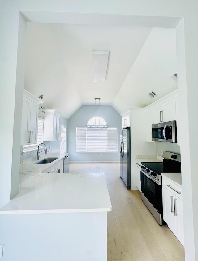 1198 Saddle Creek Dr, Fort Walton Beach, FL 32547 - kitchen with stainless steel appliances, light wood-type flooring, light countertops, lofted ceiling, and white cabinets