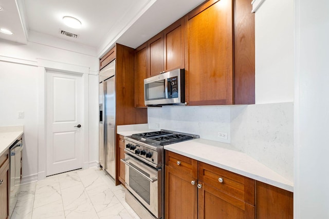 1101 Sawgrass Ct Unit 102, Panama City Beach, FL 32413 - kitchen with premium appliances, light marble finish floors, brown cabinets, and light countertops