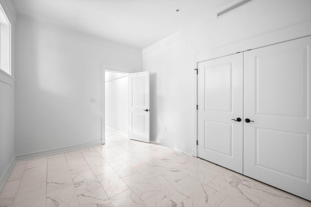 1101 Sawgrass Ct Unit 102, Panama City Beach, FL 32413 - unfurnished bedroom with light marble finish floors, a closet, and ornamental molding