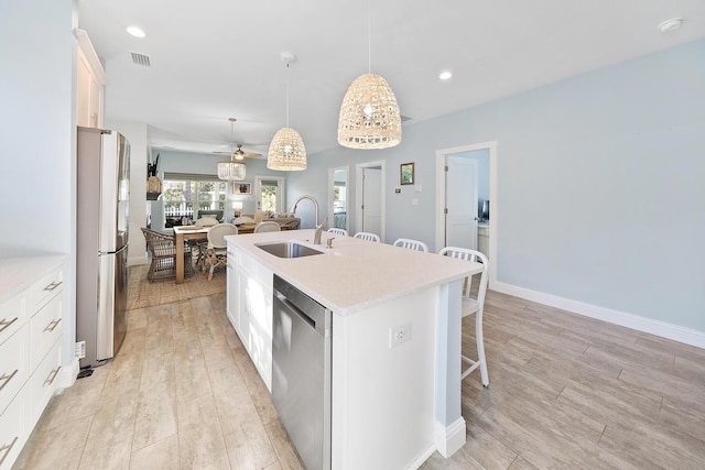 115 N Barcelona Ave, Santa Rosa Beach, FL 32459 - kitchen featuring stainless steel appliances, an island with sink, a breakfast bar area, open floor plan, and light wood-style flooring