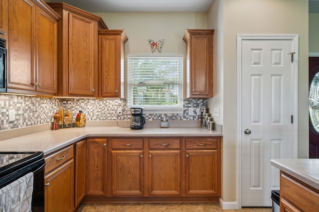4820 Griffith Rd, Holt, FL 32564 - kitchen featuring tasteful backsplash, brown cabinetry, light countertops, and black range with electric stovetop