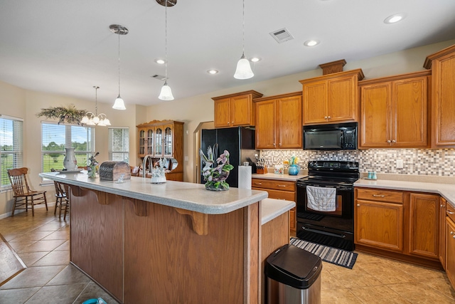 4820 Griffith Rd, Holt, FL 32564 - kitchen featuring black appliances, a kitchen breakfast bar, backsplash, brown cabinetry, and light countertops