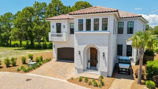 1831 Tuscana Pl, Miramar Beach, FL 32550 - mediterranean / spanish-style house featuring a tile roof, a balcony, an attached garage, decorative driveway, and stucco siding