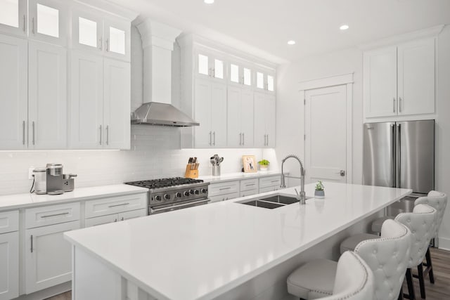 1831 Tuscana Pl, Miramar Beach, FL 32550 - kitchen featuring high quality appliances, wall chimney range hood, a breakfast bar area, a kitchen island with sink, and tasteful backsplash