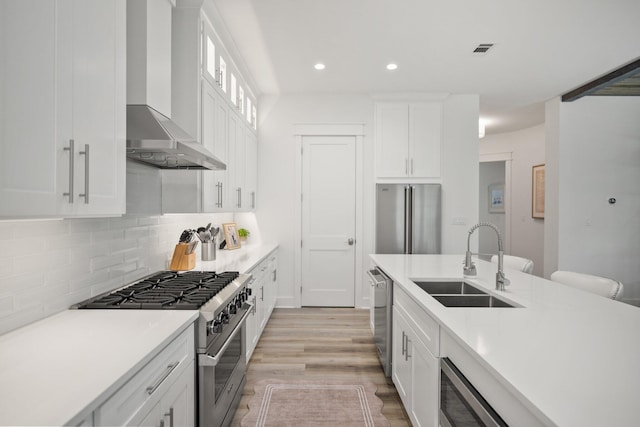 1831 Tuscana Pl, Miramar Beach, FL 32550 - kitchen with stainless steel appliances, wall chimney range hood, backsplash, white cabinetry, and light countertops