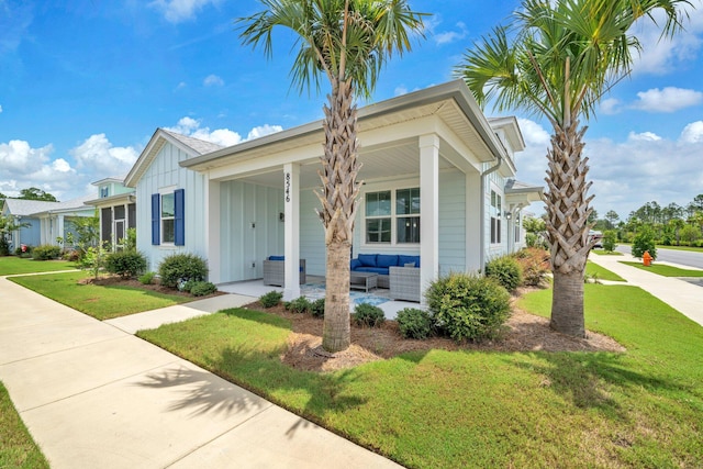 8546 Dreams Float Ct, Panama City Beach, FL 32413 - view of front facade with board and batten siding, a front yard, outdoor lounge area, and covered porch