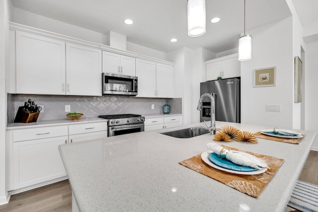 8546 Dreams Float Ct, Panama City Beach, FL 32413 - kitchen featuring stainless steel appliances, light wood finished floors, white cabinetry, pendant lighting, and backsplash