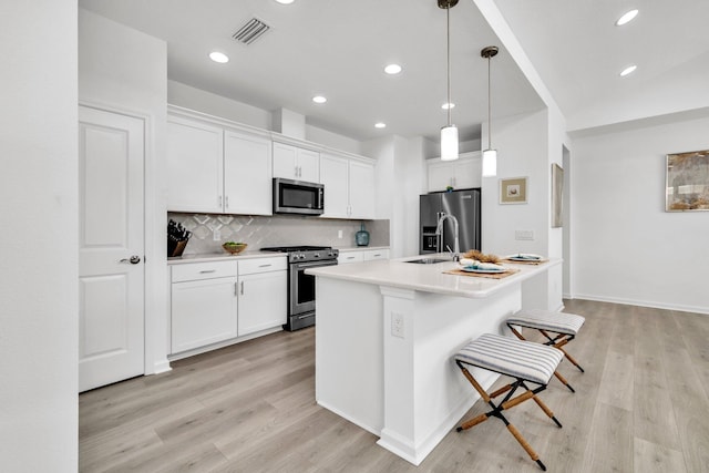 8546 Dreams Float Ct, Panama City Beach, FL 32413 - kitchen with stainless steel appliances, decorative backsplash, white cabinetry, light wood-style flooring, and light countertops