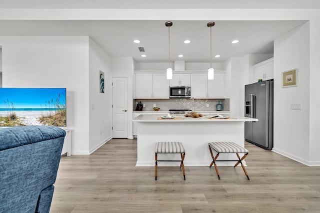 8546 Dreams Float Ct, Panama City Beach, FL 32413 - kitchen featuring high end refrigerator, stainless steel microwave, open floor plan, white cabinetry, and light countertops