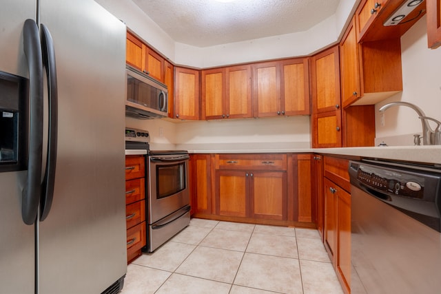 2786 Willow Bend Ct, Crestview, FL 32539 - kitchen with appliances with stainless steel finishes, brown cabinets, light countertops, light tile patterned flooring, and a textured ceiling