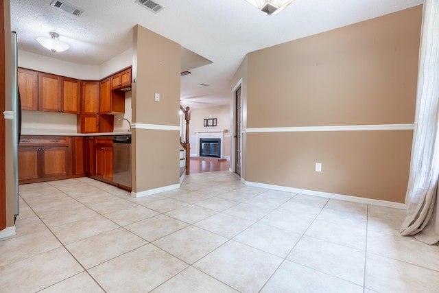 2786 Willow Bend Ct, Crestview, FL 32539 - kitchen featuring stainless steel appliances, brown cabinets, a glass covered fireplace, and light tile patterned floors
