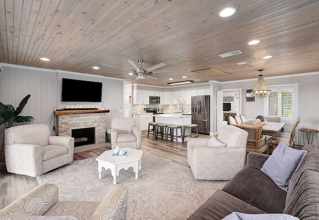 58 Montgomery St, Santa Rosa Beach, FL 32459 - living room featuring crown molding, light wood-style floors, a stone fireplace, a ceiling fan, and a chandelier