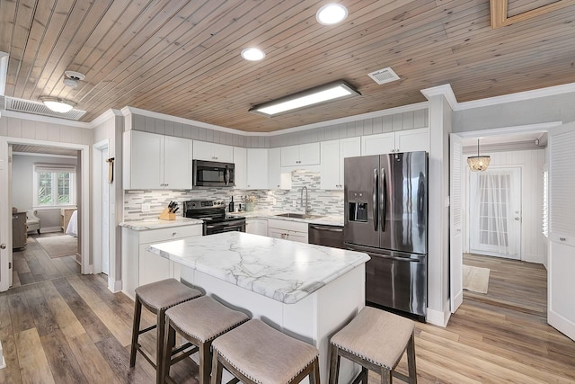 58 Montgomery St, Santa Rosa Beach, FL 32459 - kitchen with stainless steel appliances, crown molding, a breakfast bar area, backsplash, and white cabinets