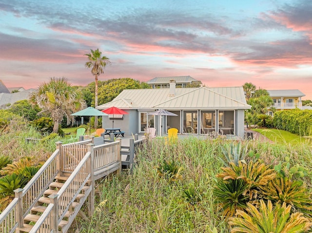 58 Montgomery St, Santa Rosa Beach, FL 32459 - back of house at dusk with a metal roof, stairs, a sunroom, stucco siding, and a standing seam roof