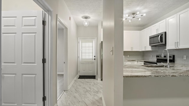 34 Herons Watch Way Unit 1202, Santa Rosa Beach, FL 32459 - kitchen featuring appliances with stainless steel finishes, light stone countertops, tasteful backsplash, light marble finish flooring, and white cabinets