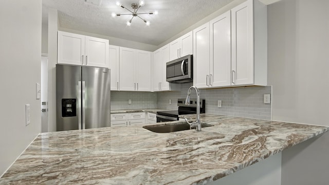 34 Herons Watch Way Unit 1202, Santa Rosa Beach, FL 32459 - kitchen with stainless steel appliances, light stone counters, a chandelier, and a textured ceiling