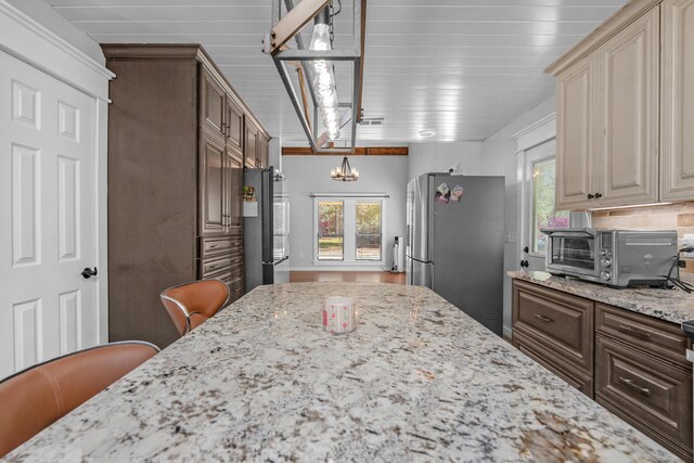 6539 Robar Tesora St, Navarre, FL 32566 - kitchen with freestanding refrigerator, a chandelier, plenty of natural light, and light stone counters