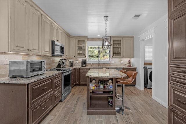 6539 Robar Tesora St, Navarre, FL 32566 - kitchen featuring open shelves, appliances with stainless steel finishes, washer / clothes dryer, cream cabinets, and glass insert cabinets
