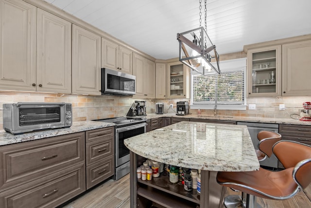 6539 Robar Tesora St, Navarre, FL 32566 - kitchen with stainless steel appliances, cream cabinetry, open shelves, decorative backsplash, and glass insert cabinets