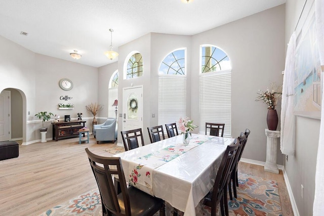 131 Wedgewood Ln, Crestview, FL 32536 - dining room featuring light wood-style flooring, arched walkways, and a high ceiling