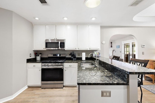 131 Wedgewood Ln, Crestview, FL 32536 - kitchen with appliances with stainless steel finishes, arched walkways, a breakfast bar area, light wood-style flooring, and recessed lighting