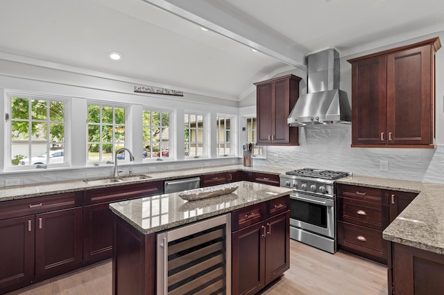 1510 Match Point Ln Unit 303, Panama City Beach, FL 32413 - kitchen with beverage cooler, wall chimney range hood, appliances with stainless steel finishes, light wood-style floors, and light stone countertops