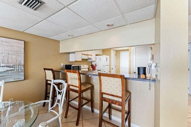 11483 Front Beach Rd Unit 1004, Panama City Beach, FL 32407 - kitchen featuring freestanding refrigerator, a drop ceiling, a breakfast bar, a peninsula, and under cabinet range hood