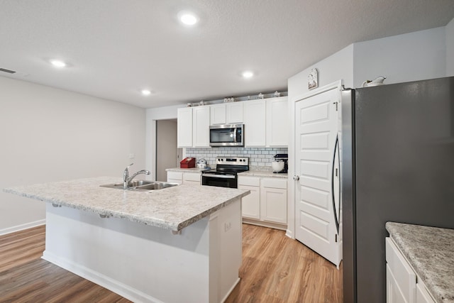 6721 Sarah Ann Way, Laurel Hill, FL 32567 - kitchen with stainless steel appliances, light wood finished floors, an island with sink, white cabinetry, and recessed lighting