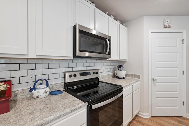6721 Sarah Ann Way, Laurel Hill, FL 32567 - kitchen featuring stainless steel microwave, electric stove, light countertops, white cabinetry, and tasteful backsplash