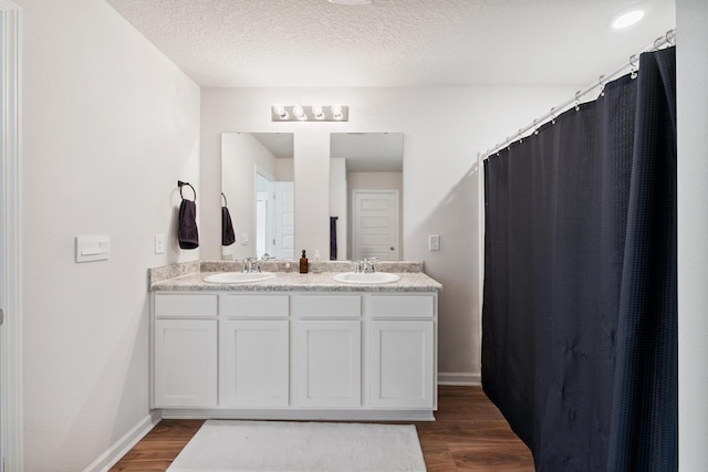 6721 Sarah Ann Way, Laurel Hill, FL 32567 - full bathroom with double vanity, wood finished floors, a textured ceiling, and a shower with shower curtain