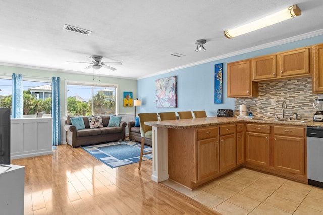 445 Gulf Shore Dr Unit 206, Destin, FL 32541 - kitchen with ceiling fan, stainless steel dishwasher, ornamental molding, decorative backsplash, and brown cabinets