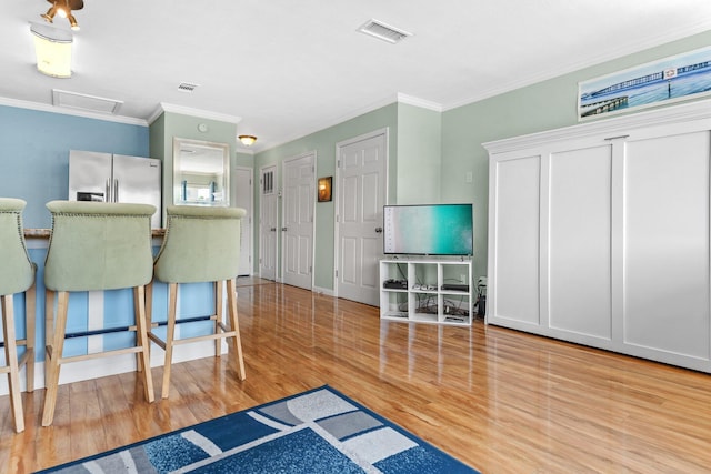 445 Gulf Shore Dr Unit 206, Destin, FL 32541 - kitchen with stainless steel fridge, ornamental molding, wood finished floors, and a breakfast bar