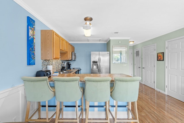 445 Gulf Shore Dr Unit 206, Destin, FL 32541 - kitchen featuring appliances with stainless steel finishes, a peninsula, ornamental molding, a kitchen bar, and decorative backsplash