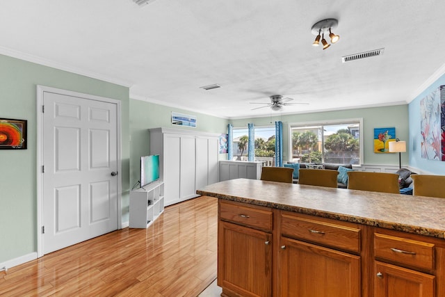 445 Gulf Shore Dr Unit 206, Destin, FL 32541 - kitchen with light wood-type flooring, crown molding, ceiling fan, and brown cabinetry
