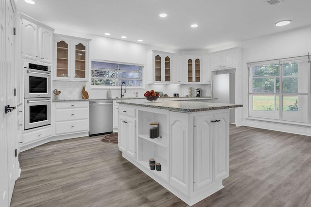 1005 Shalimar Point Dr, Shalimar, FL 32579 - kitchen featuring stainless steel appliances, stone counters, white cabinetry, a center island, and glass insert cabinets