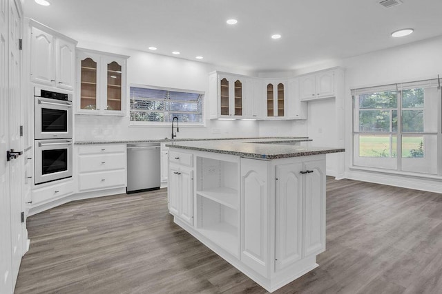 1005 Shalimar Point Dr, Shalimar, FL 32579 - kitchen with stainless steel appliances, dark stone counters, white cabinetry, a kitchen island, and backsplash