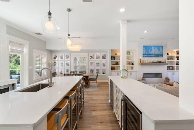 192 Lake Pointe Dr, Santa Rosa Beach, FL 32459 - kitchen with wine cooler, a large island with sink, a fireplace, wood finished floors, and light countertops