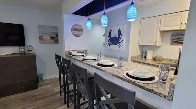 17614 Front Beach Rd Unit 12E, Panama City Beach, FL 32413 - kitchen featuring white cabinets, wood finished floors, light stone counters, pendant lighting, and a breakfast bar
