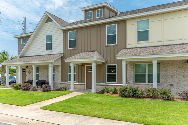 400 Mattie M Kelly Blvd Unit 7, Destin, FL 32541 - view of front of property featuring board and batten siding, a front lawn, a shingled roof, a porch, and brick siding