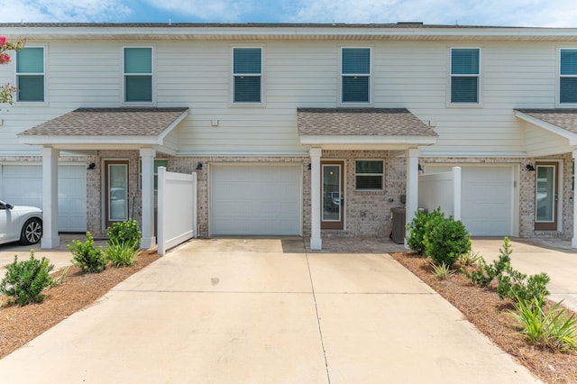 400 Mattie M Kelly Blvd Unit 7, Destin, FL 32541 - view of property featuring an attached garage, concrete driveway, brick siding, and roof with shingles