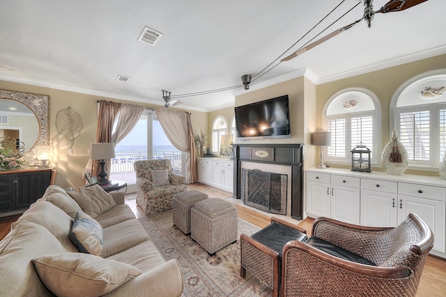 2905 Scenic Gulf Dr, Miramar Beach, FL 32550 - living room with crown molding, a fireplace, and light wood-style floors