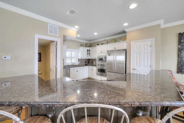 2905 Scenic Gulf Dr, Miramar Beach, FL 32550 - kitchen with built in appliances, a breakfast bar, crown molding, a peninsula, and glass insert cabinets