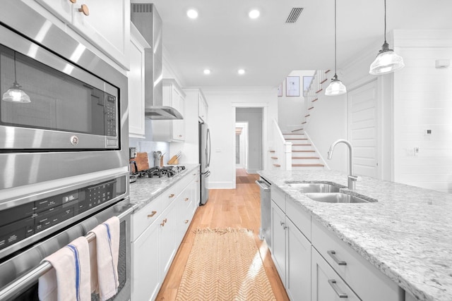 49 Clipper St, Inlet Beach, FL 32461 - kitchen with appliances with stainless steel finishes, wall chimney exhaust hood, white cabinetry, hanging light fixtures, and light wood-style floors