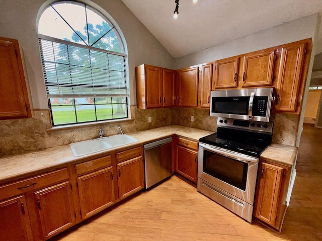 7167 Manatee St, Navarre, FL 32566 - kitchen with appliances with stainless steel finishes, brown cabinetry, light wood-type flooring, light countertops, and vaulted ceiling