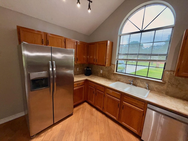 7167 Manatee St, Navarre, FL 32566 - kitchen with stainless steel appliances, light wood finished floors, brown cabinetry, and lofted ceiling