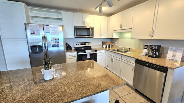 9902 S Thomas Dr Unit 933, Panama City Beach, FL 32408 - kitchen with stainless steel appliances, white cabinets, light tile patterned flooring, dark stone countertops, and rail lighting