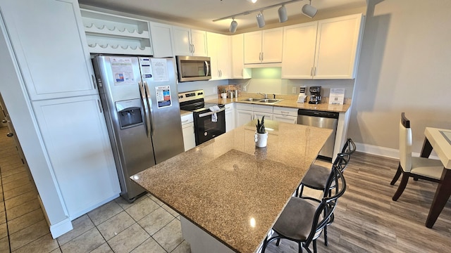 9902 S Thomas Dr Unit 933, Panama City Beach, FL 32408 - kitchen with appliances with stainless steel finishes, a kitchen breakfast bar, light stone countertops, white cabinets, and a center island