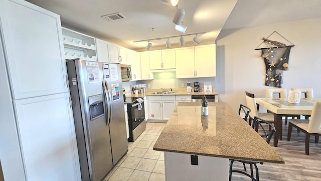 9902 S Thomas Dr Unit 933, Panama City Beach, FL 32408 - kitchen with stainless steel appliances, a kitchen island, a breakfast bar, open shelves, and white cabinetry