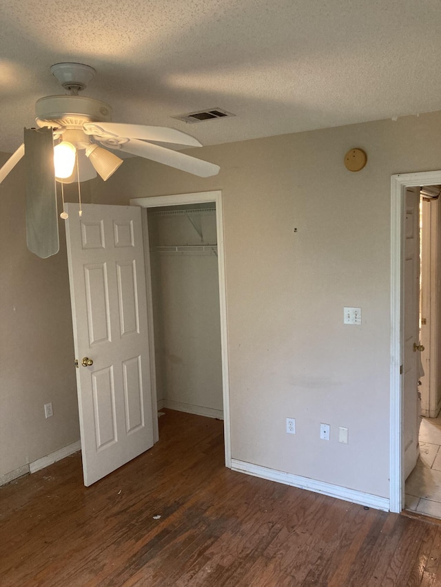 4627 Windstarr Dr, Destin, FL 32541 - unfurnished bedroom with a textured ceiling, wood finished floors, a closet, ceiling fan, and a walk in closet