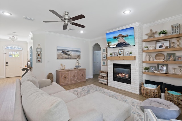 1009 Forest Shore Dr, Miramar Beach, FL 32550 - living area featuring ornamental molding, arched walkways, ceiling fan, light wood-type flooring, and a large fireplace